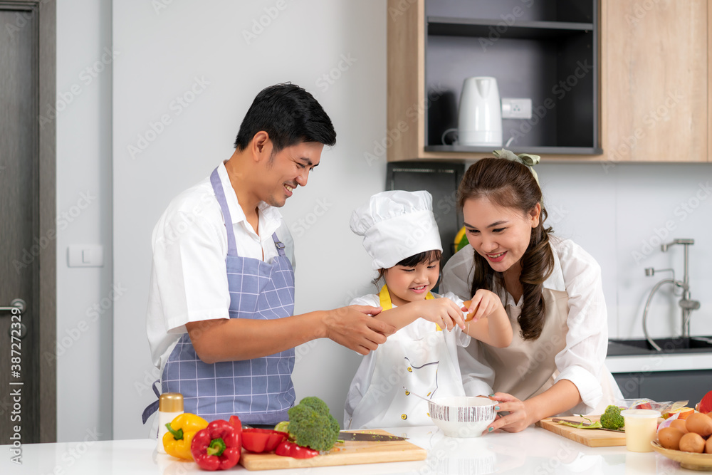 Young Asian love family are preparing food dinner on table in the kitchen which father and mother teaching daughter to cooking food on the day at home..