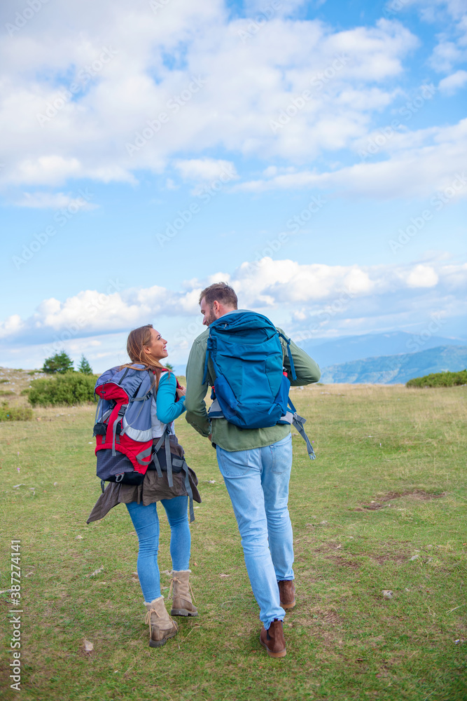 Happy couple hiking and enjoying a valley view. Photo taken from back.