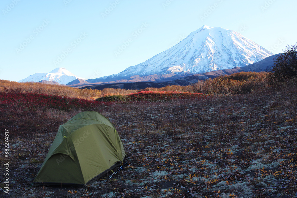 Autumn in Kamchatka, tourism tent on the background of volcanoes. Travel across Russia.  Hiking camp under the mountain. Russian tourism.  Morning frosts. Rest at nature. Active lifestyle