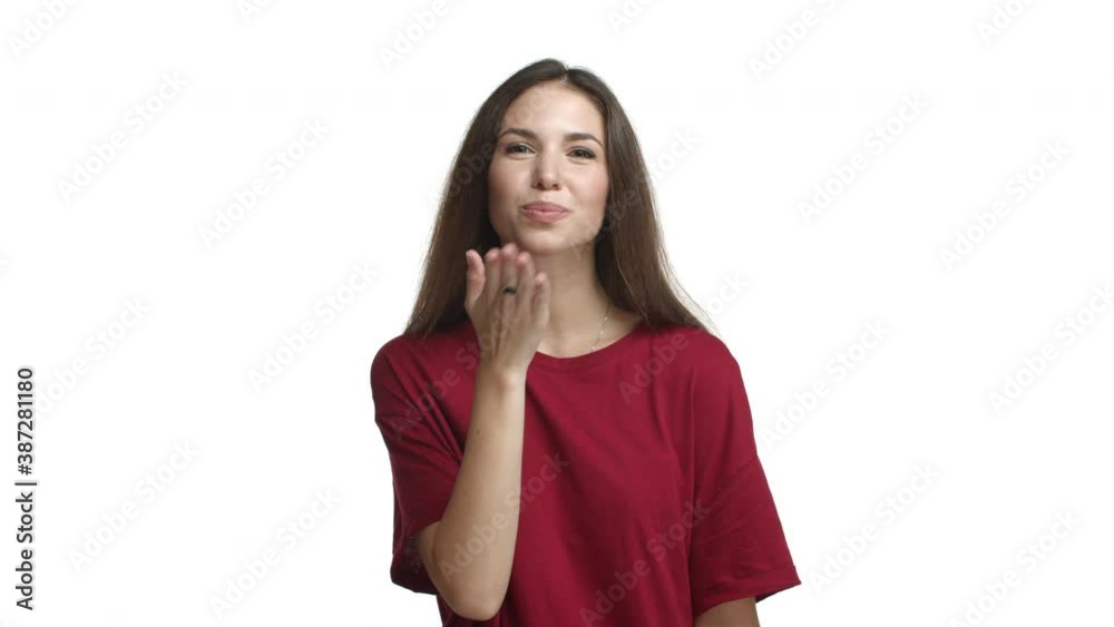 Attrative brunette girl in red t-shirt looking flirty, sending air kiss at camera and smiling coquettish, standing over white background Attrative brunette girl in red t-shirt looking flirty, sending air kiss at camera and smiling coquettish, standing over white background