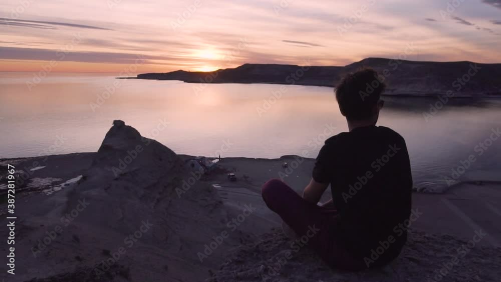 Young Model seated on top of a mountain watching the sunset - Wide shot Young Model seated on top of a mountain watching the sunset - Wide shot
