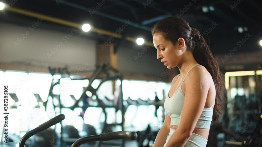 Exhausted fit girl sitting in sport club. Sport woman making break at gym