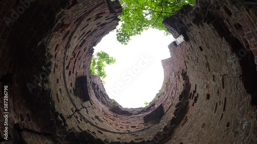 Looking up to the sky from the bottom of old tower ruins and spinning, tree tops during the daytime