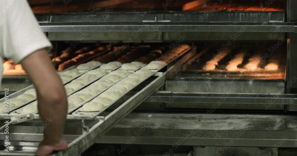 Baker Pushing The Manual Loader With Dough Inside The Deck Oven In The Bakery. - medium shot Baker Pushing The Manual Loader With Dough Inside The Deck Oven In The Bakery. - medium shot