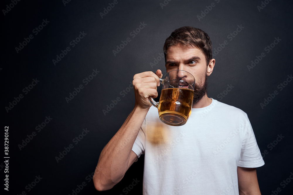 man with a mug of beer in a white t-shirt emotions lifestyle drunk on a dark isolated background man with a mug of beer in a white t-shirt emotions lifestyle drunk on a dark isolated background