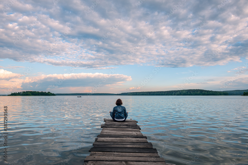 Girl sitting in lotus position on a wooden pier