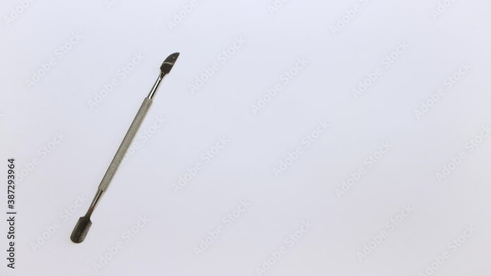 A man's hand places a metal manicure spatula on the table on the left. There is a place to insert text. Self-care nails. Isolated video on a white background. Close-up. Warm, soft light. UHD. A man's hand places a metal manicure spatula on the table on the left. There is a place to insert text. Self-care nails. Isolated video on a white background. Close-up. Warm, soft light. UHD.