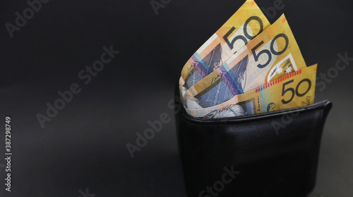 Fotografía Close up looking down on an isolated black purse or wallet holding 50 fifty dollar notes