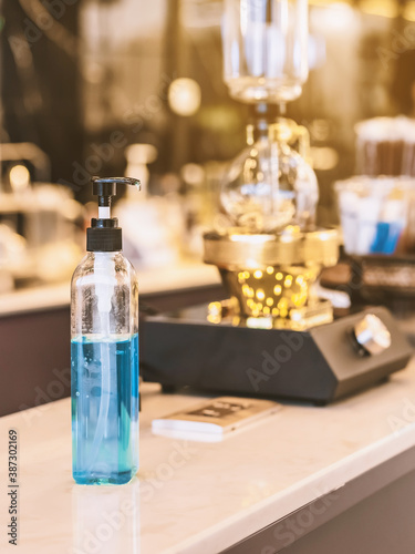 Blue alcohol gel bottle for hands cleaning to prevent the spreading of the Corona virus (Covid-19), Place the entrance service for customers  in the cafe. Healthcare concept. New normal lifestyle. © JinnaritT
