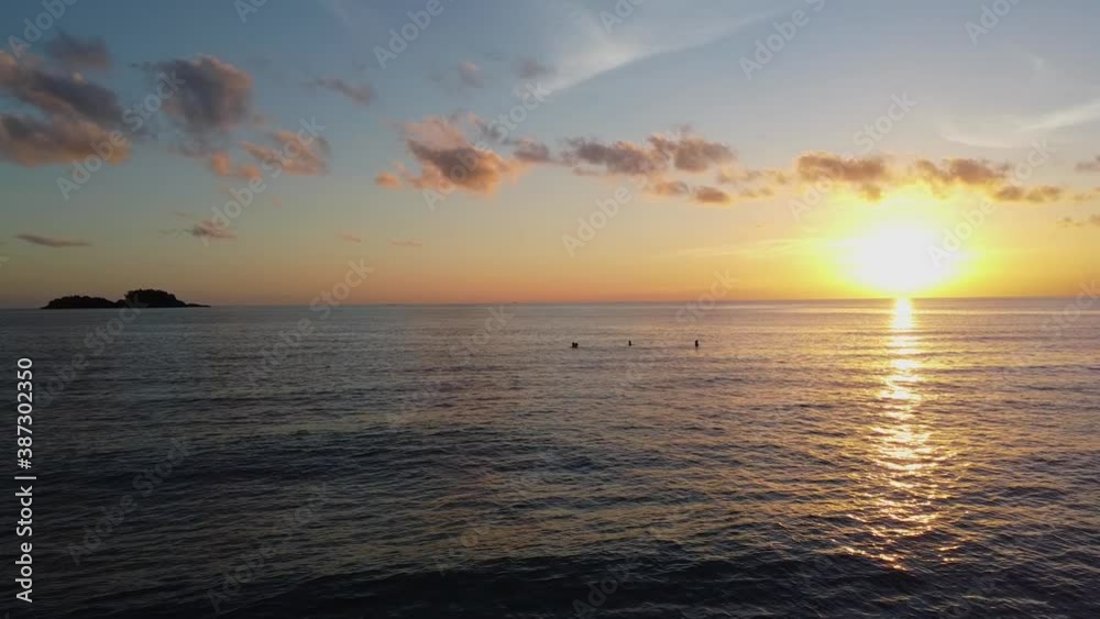AERIAL: Drone is Traveling Low Above the Calm Coastal Waters, People Swim on the Sunset with Islands on the Background. Beautiful Koh Chang Island, Thailand, Asia. AERIAL: Drone is Traveling Low Above the Calm Coastal Waters, People Swim on the Sunset with Islands on the Background. Beautiful Koh Chang Island, Thailand, Asia.