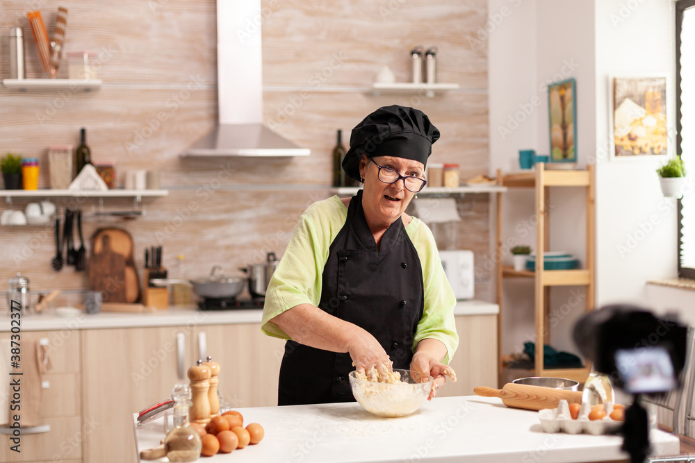 Senior woman recording live video for culinary vlog at home. Retired blogger chef influencer using internet technology communicating, shooting blogging on social media with digital equipment Senior woman recording live video for culinary vlog at home. Retired blogger chef influencer using internet technology communicating, shooting blogging on social media with digital equipment