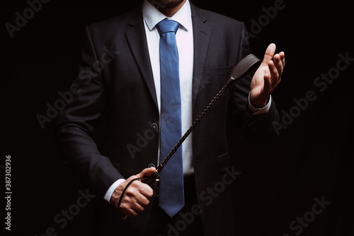 male dominant holds a leather whip Flogger for hard BDSM sex photo