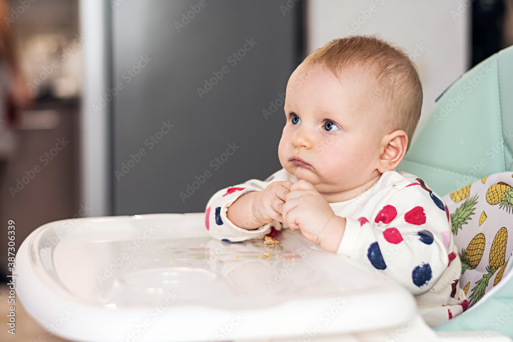 Little baby eating sitting on a child chair. Cute baby eats Little baby eating sitting on a child chair. Cute baby eats