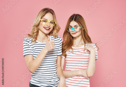 Two women in striped T-shirts trendy glasses communication Friendship together pink background © SHOTPRIME STUDIO