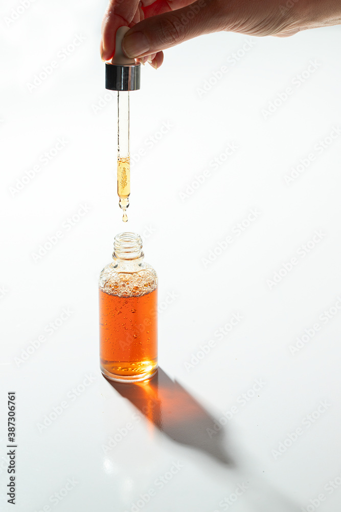 hand holding a dropper with natural serum on white background. Skin care concept. Copy space. hand holding a dropper with natural serum on white background. Skin care concept. Copy space.