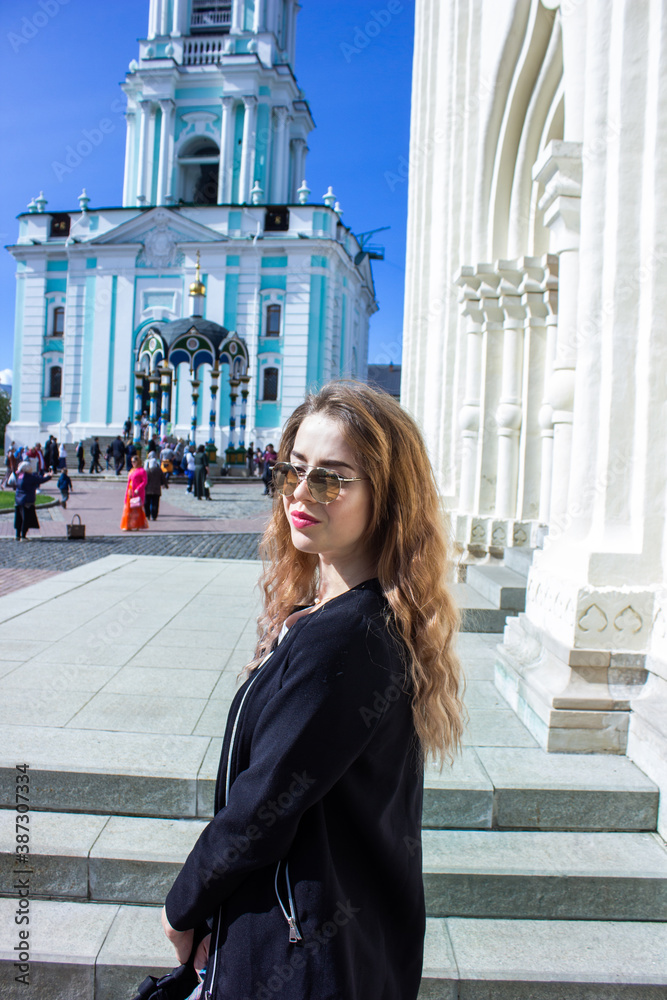 Fototapeta premium A young woman in front of the Trinity-Sergius Lavra in Sergiev Posad. Moscow region. Russia. came out