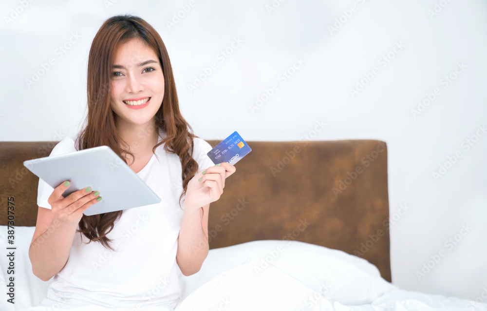 Happy asian woman doing online shopping at home, Women shopping online with credit card and laptop on the bed at home Happy asian woman doing online shopping at home, Women shopping online with credit card and laptop on the bed at home