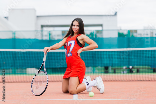 Beautiful female tennis player on tennis court. Red dress. © Ivan Zelenin