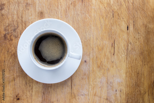A cup of coffee in a white cup on a wooden background