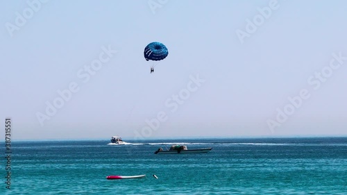 Parasailing at Fujairah in United Arab Emirates, extreme Sport. Tourists para sailing - popular entertainment for holiday travelers on Fujairah Beach UAE. Concept of vacation fun.