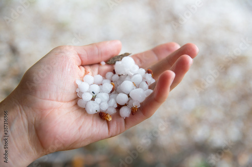 A large hail lies in a woman's palm.