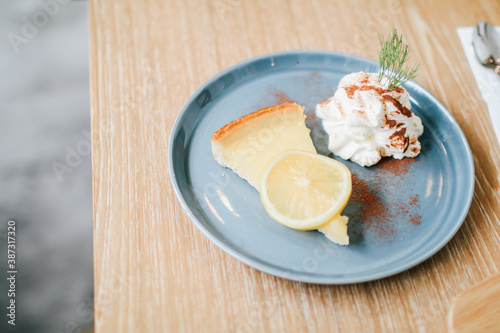  Lemon tart with whipping cream, sliced on a white plate.Delicious, appetizing, homemade dessert. Traditional french sweet pastry tart.