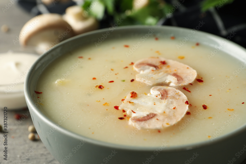 Concept of tasty lunch with bowl of mushroom soup on gray background Concept of tasty lunch with bowl of mushroom soup on gray background