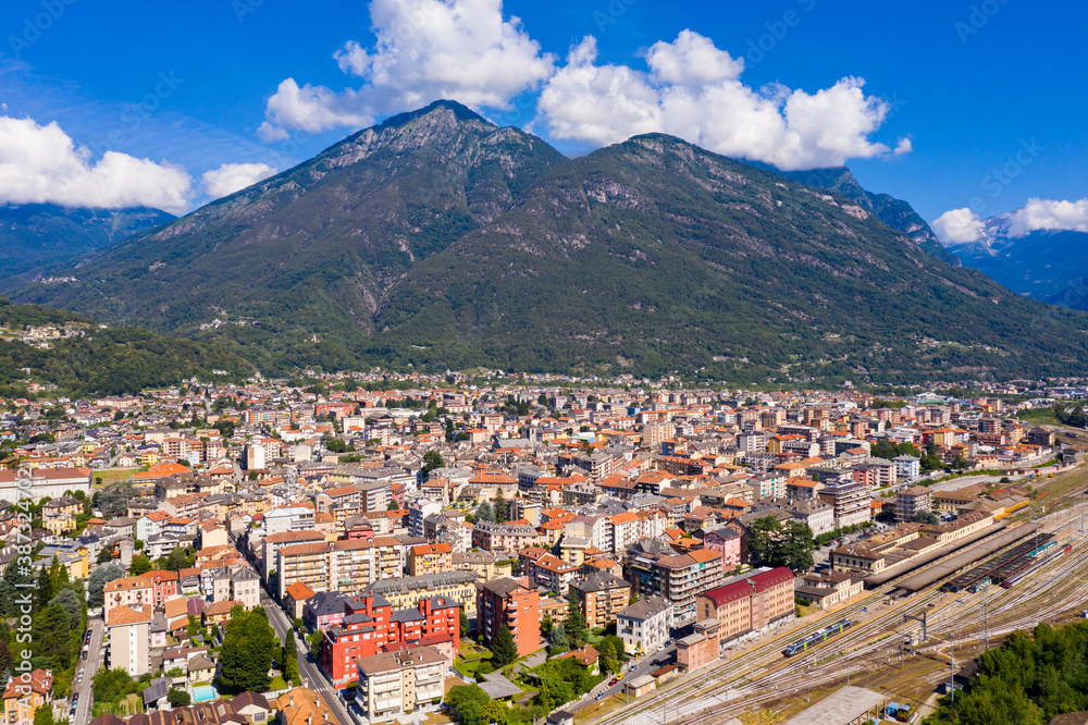 Summer view from drone of small town of Domodossola in Ossola valley surrounded by green Alps overlooking railway, Italy .