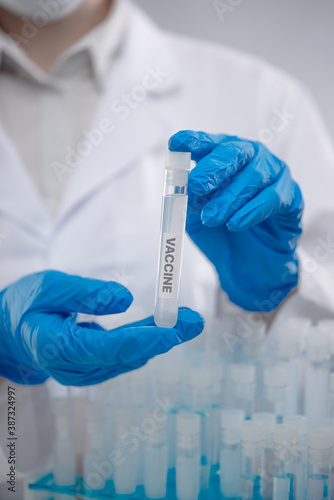 Close-up view of hands in protective blue gloves keeps biological tube with vaccine. Healthcare and medical concept.
