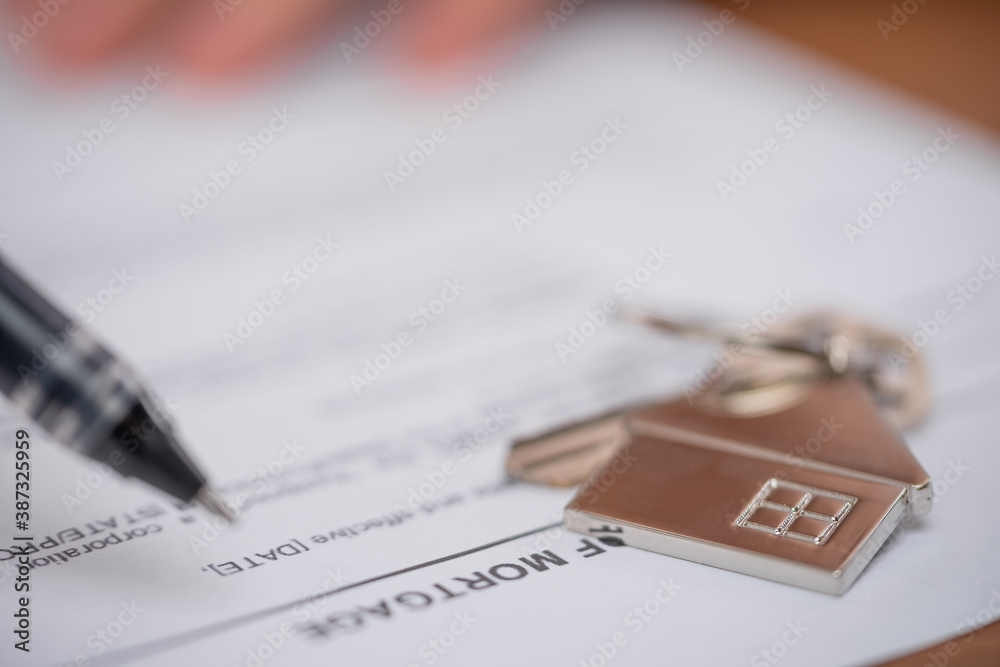 Mortgage loan agreement application with pan and key and home shaped keychain. Signing agreement contract. New home concept.