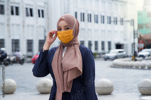 Asian muslim woman wearing hijab or jilbab and fabric mask at malioboro area, Yogyakarta. covid-19 virus pandemic new normal concept photo