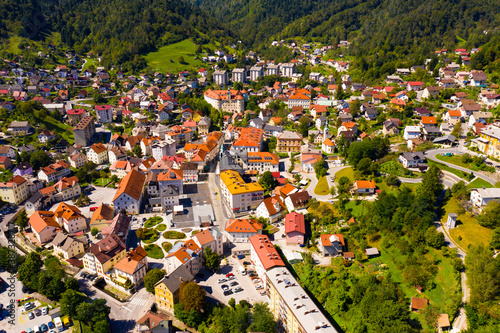 General aerial view of small town of Idrija between green hills in western Slovenia on sunny day photo