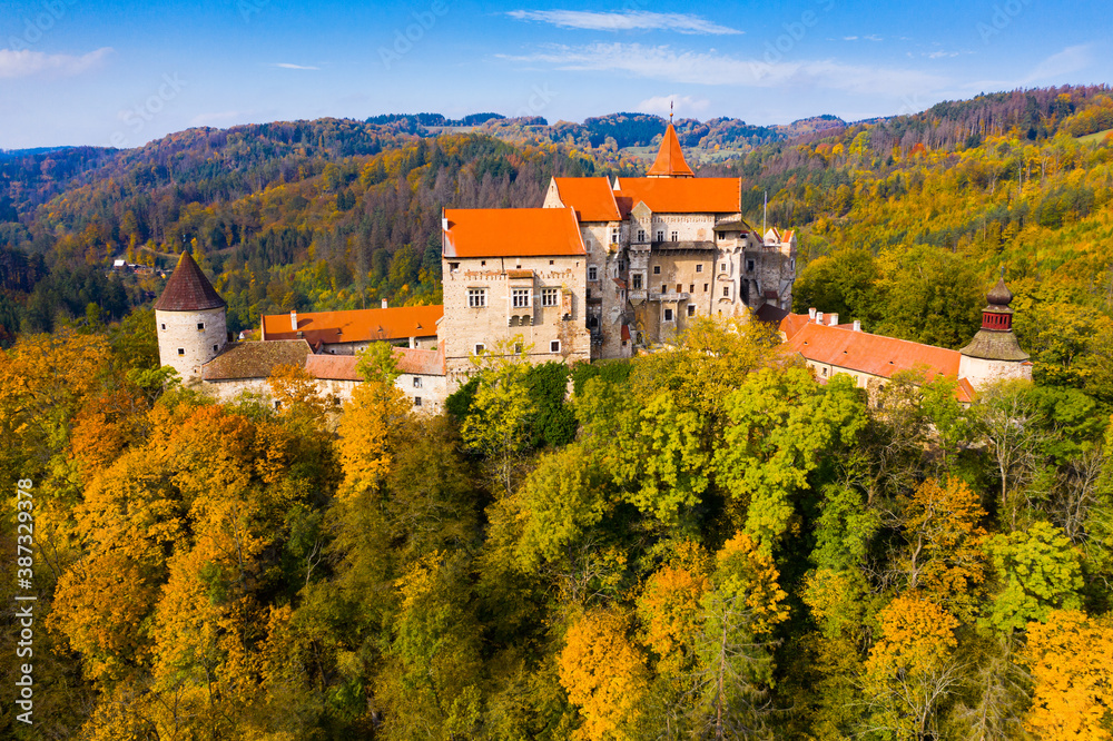 Picturesque autumn landscape with imposing historic Pernstejn Castle on rock above village of Nedvedice, Czech Republic