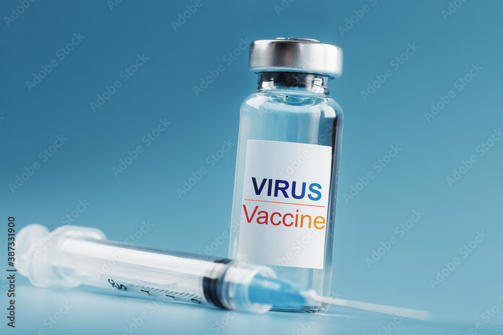 Ampoule and syringe with the vaccine against the Virus against diseases on a blue background. Ampoule and syringe with the vaccine against the Virus against diseases on a blue background.