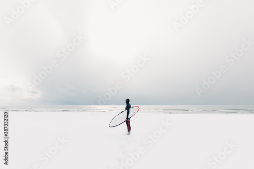 Snowy winter and surfer with surfboard. Winter and surfer in wetsuit.