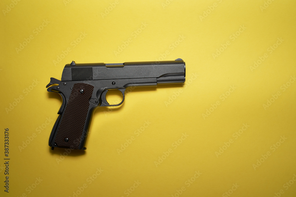 Big black gun pistol on yellow background.