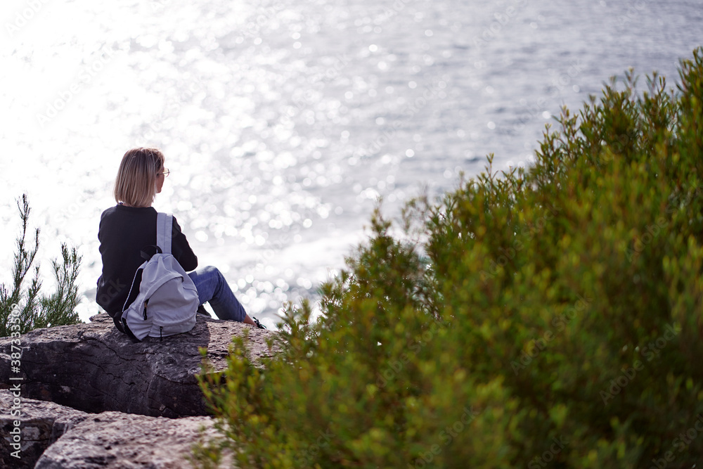 Tourism concept. Young traveling woman with rucksack enjoying ocean view.