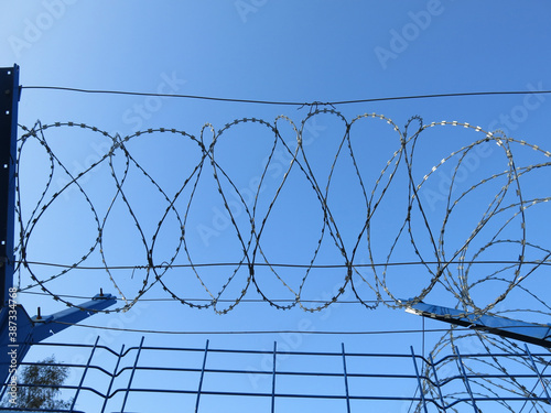 barbed wire against a clear blue sky  like a prison