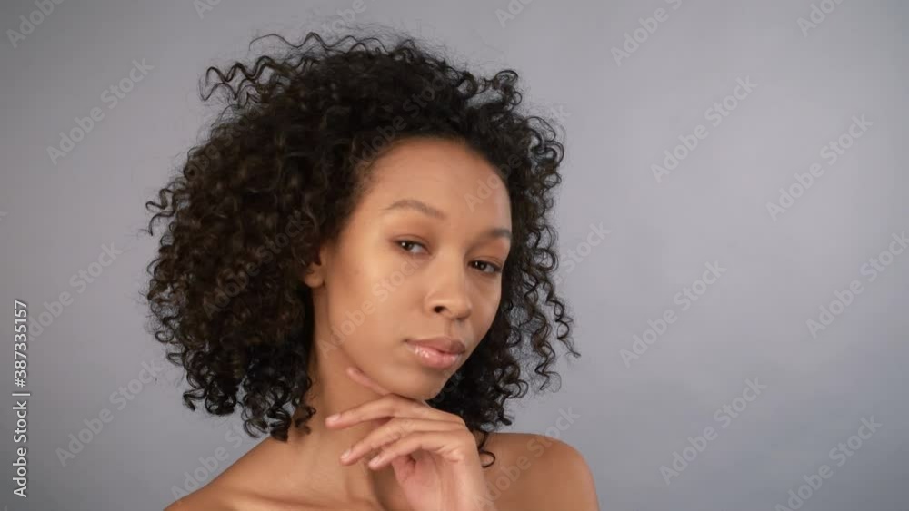 close-up portrait. attractive young female african american woman face gently touching facial skin on gray isolated background. 4K close-up portrait. attractive young female african american woman face gently touching facial skin on gray isolated background. 4K