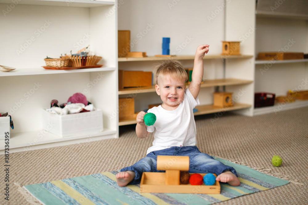 child toddler plays with balls and cylinders, developing sensory activities in montessori and earlier development of children, independence of babies