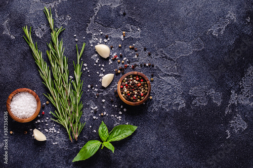 Herbs and condiments on black stone background.