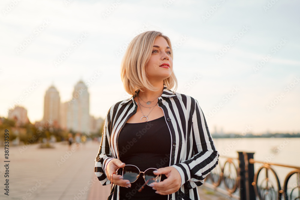 Fototapeta premium Outdoor portrait of happy young woman on city promenade.