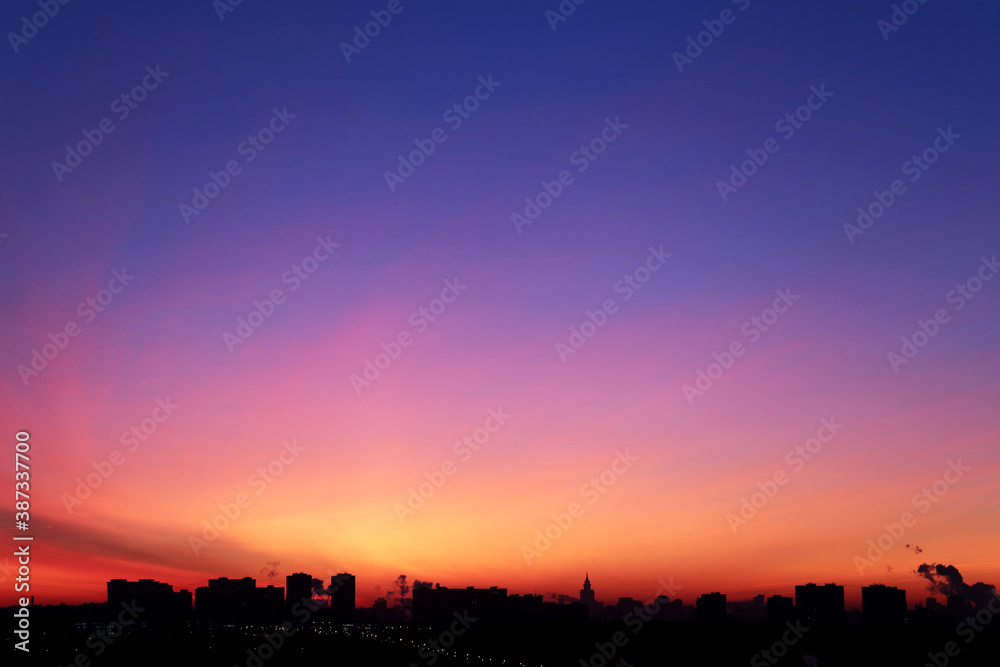 Sunrise over the city, scenic view. Pink-blue sky in soft colors sky above silhouettes of high-rise buildings, colorful cityscape for background