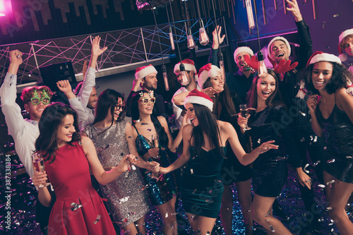 Photo of people hold glass sparkling wine falling sequins short dress santa headband hat illumination modern club indoors