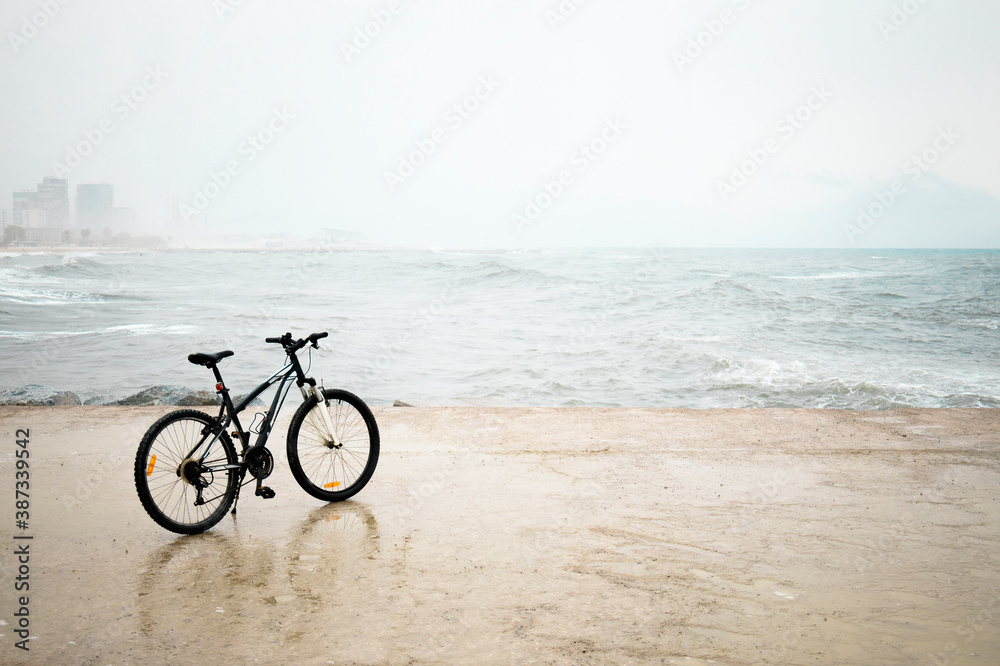 Alone Black Bicycle on the beach on rainy day with waves