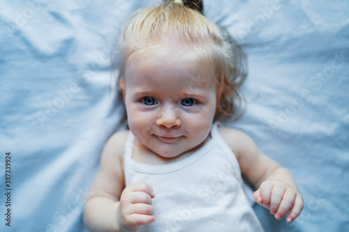 Adorable happy baby girl lying on the bed.