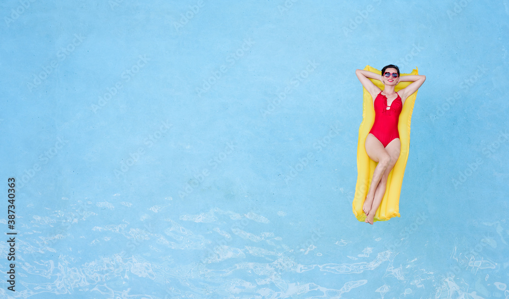 Enjoying suntan. Tropical vacation concept. Top view of young woman on the yellow air mattress in the swimming pool.