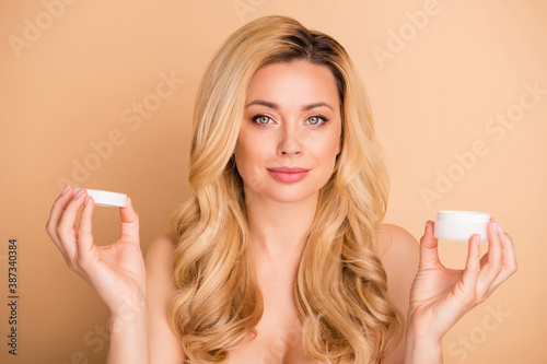 Close-up portrait of her she nice-looking attractive charming cute lovely confident wavy-haired lady holding in hands new cream clean clear soft shine flawless skin isolated on beige pastel background photo