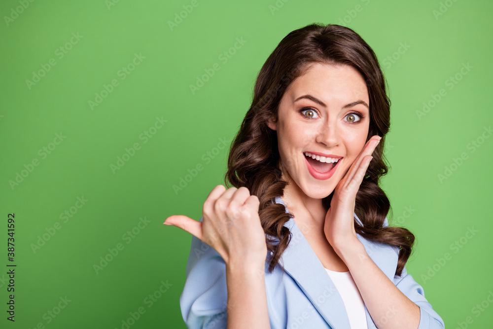 Photo of lovely woman curly hairdo direct thumb empty space hand cheek wear blue blazer isolated green color background Photo of lovely woman curly hairdo direct thumb empty space hand cheek wear blue blazer isolated green color background