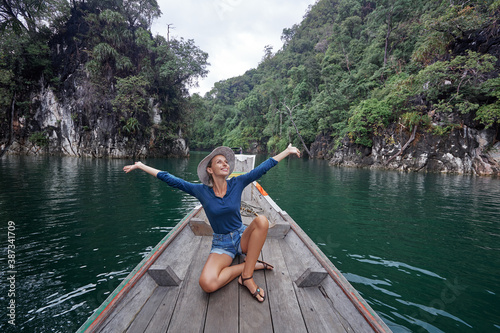 Happy vacation in Thailand. Pretty young woman taking sailing Khao Sok National Park lake on traditional longtail boat. © luengo_ua